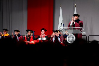 Dario Gil standing on stage clapping for graduates at Doctor of Philosophy Hooding.