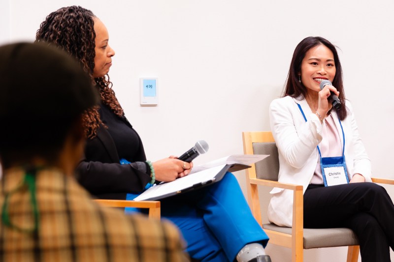 A panelist speaking and smiling into a microphone. 