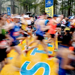 A time lapse photo of runners crossing the start line of the Boston Marathon.