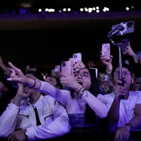 A crowd of screaming fans at a large concert venue.