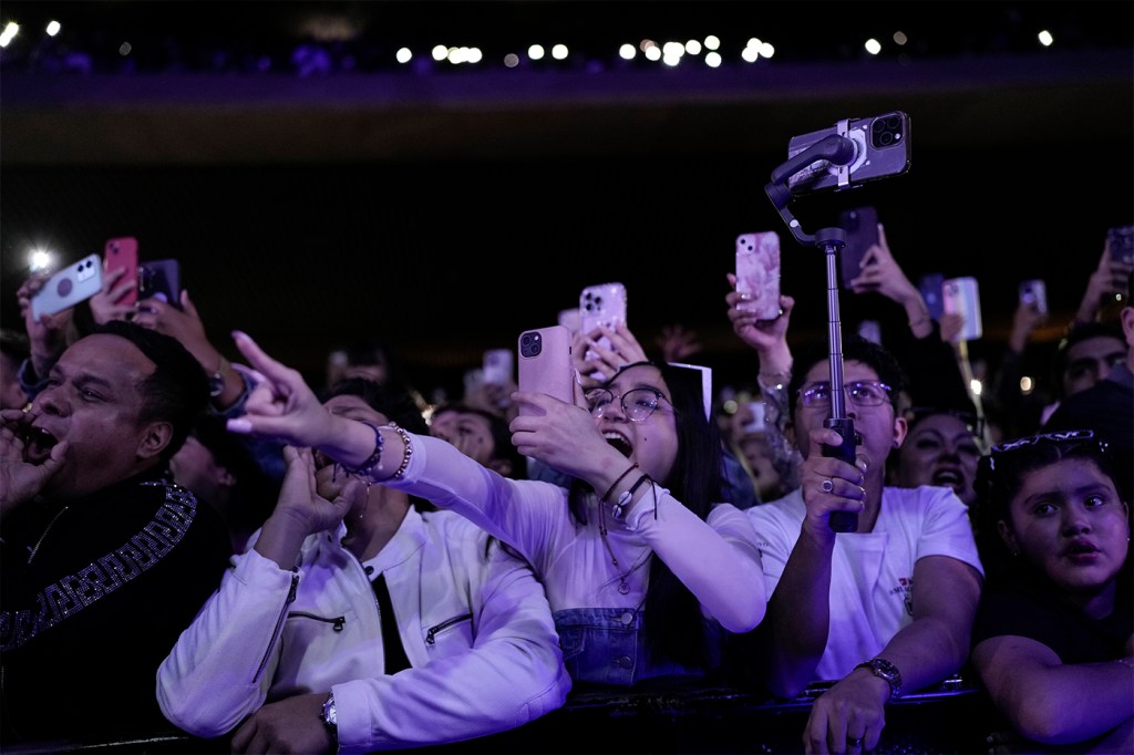 A crowd of screaming fans at a large concert venue.