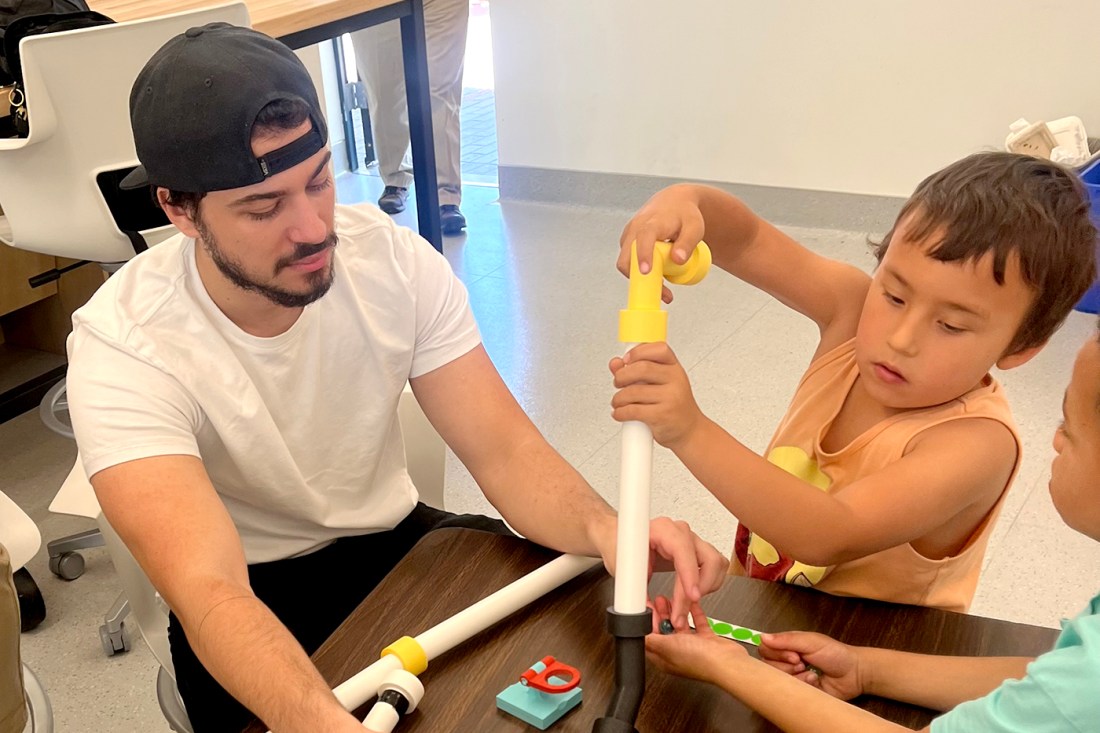 An elementary school student testing a toy in front of an Engineering student.