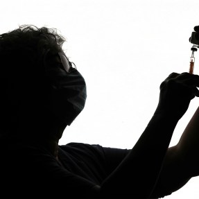 Silhouette of a person filling a syringe.