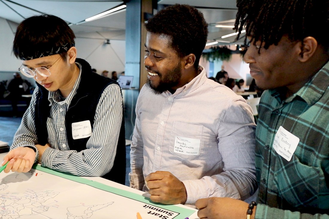 Three people standing next to each other looking at a map. 