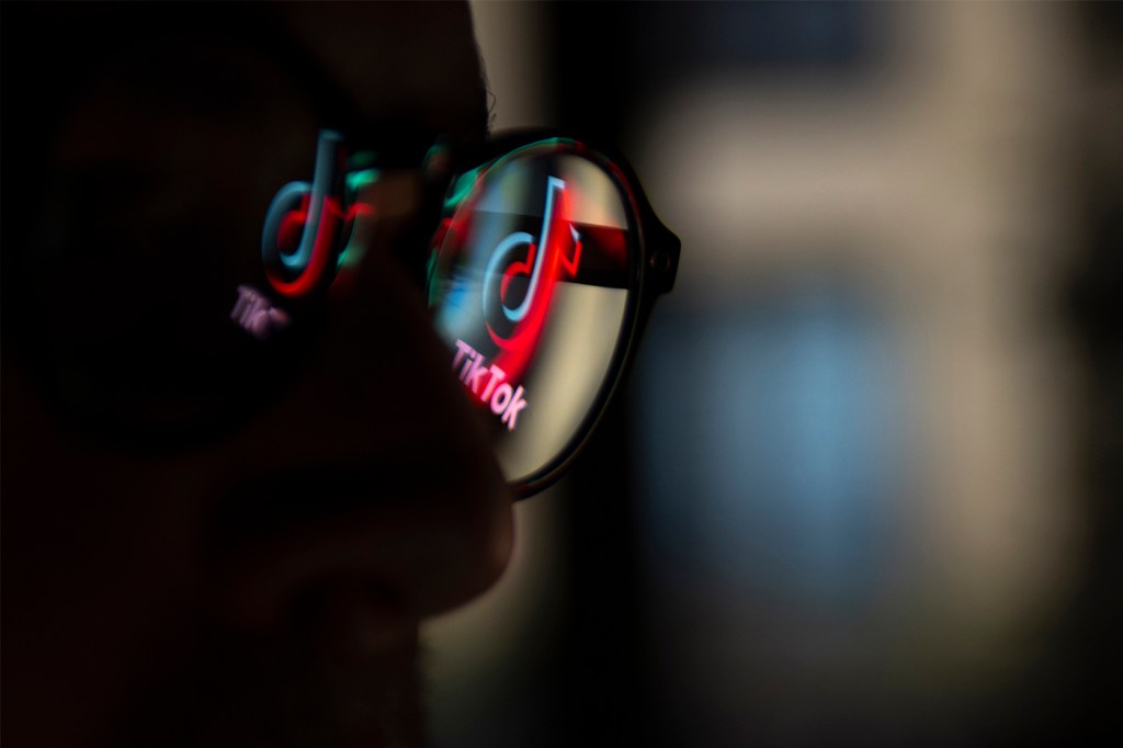 TikTok logo reflected on some glasses in a dark room.