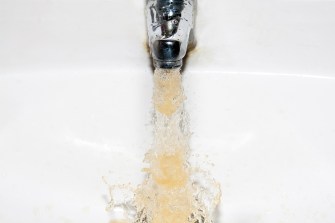 Brown water coming out of a faucet into a white sink.