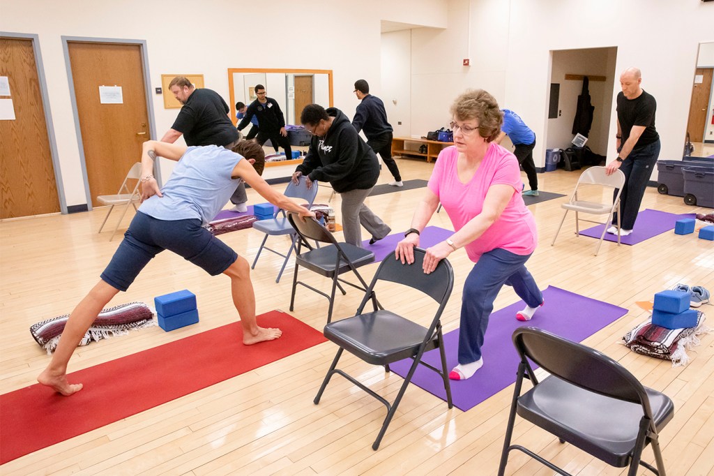 People in the yoga studio doing yoga poses on mats.