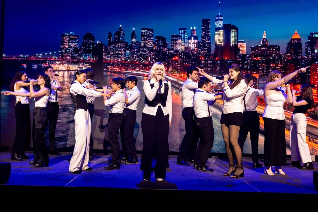 A group of people singing on stage at the Experience Powered by Northeastern event. 