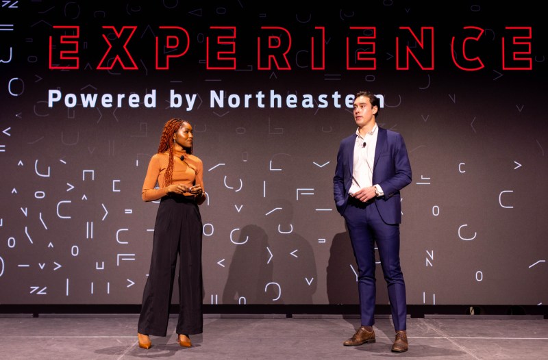 Two people standing on stage at the Experience Powered by Northeastern event.
