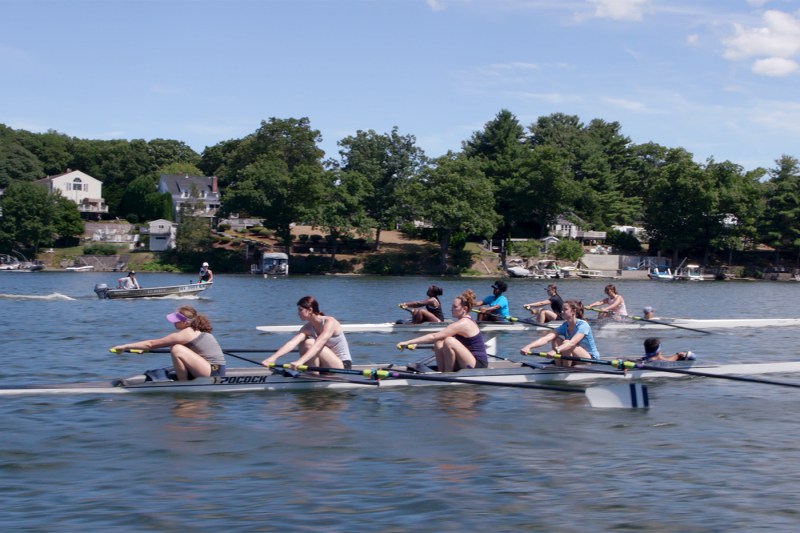 Two rowing teams move across a river.