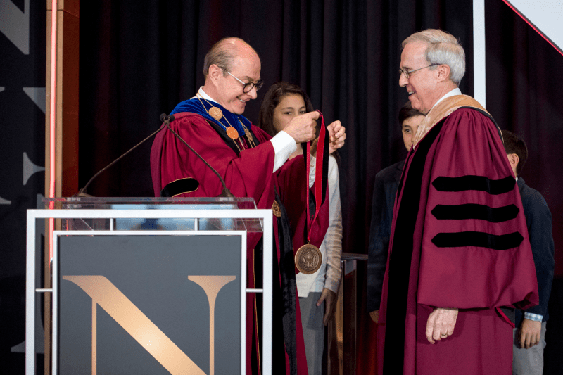 President Aoun holding up a gold medal in fron tof Henry Nasella.