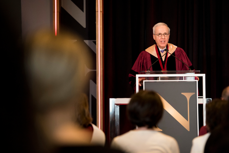 Henry J. Nasella, wearing regalia, speaks at a podium after receiving an award.