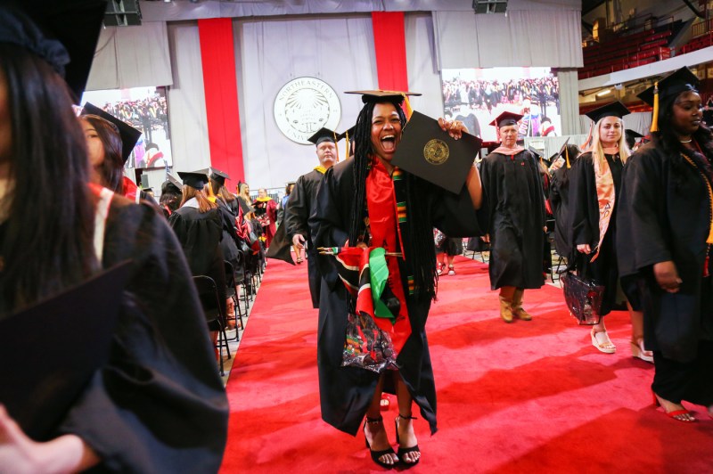 Graduate holding up their diploma at the Bouve commencement ceremony.