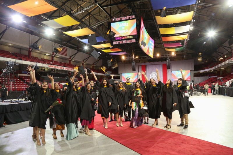 Graduates throwing their caps in the air at the Bouve commencement ceremony.