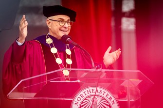 President Aoun standing in front of a microphone gesturing and smiling at the graduation ceremony.