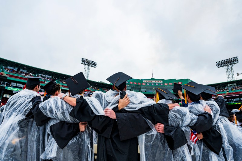 Graduates wearing ponchos with their arms over each other's shoulders. 