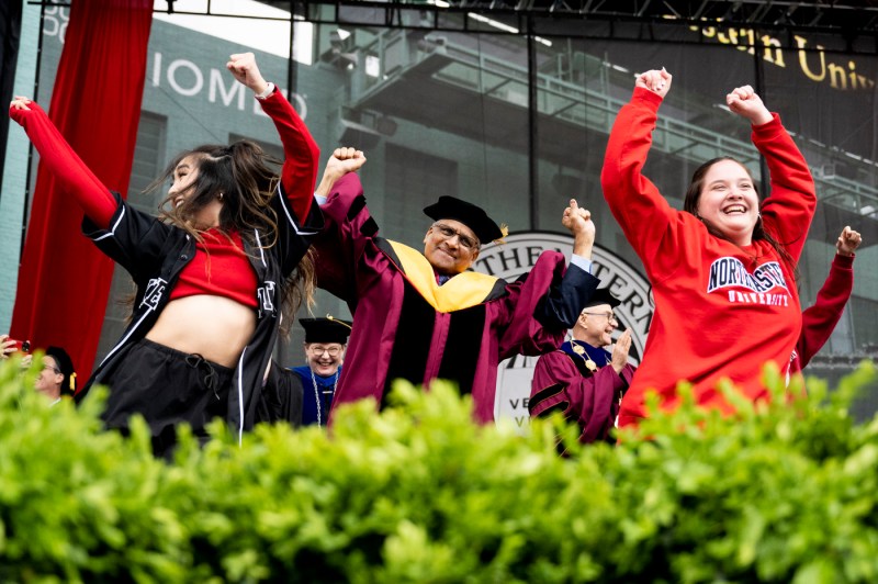 Students dancing on stage with the graduate Commencement speaker. 