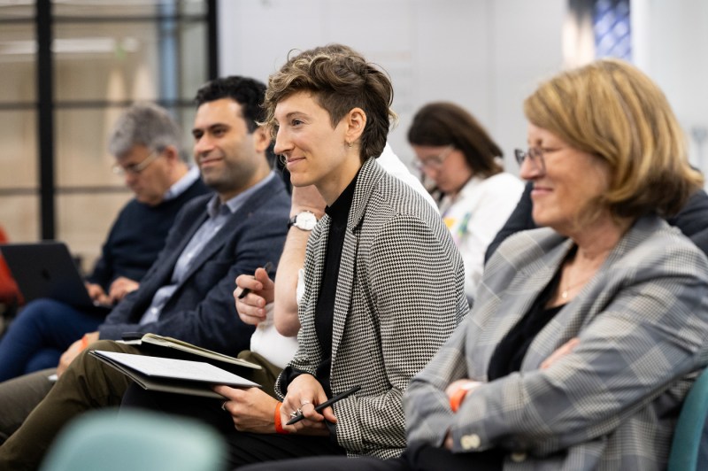 Audience members smiling while listening to Melanie Dawes speak.