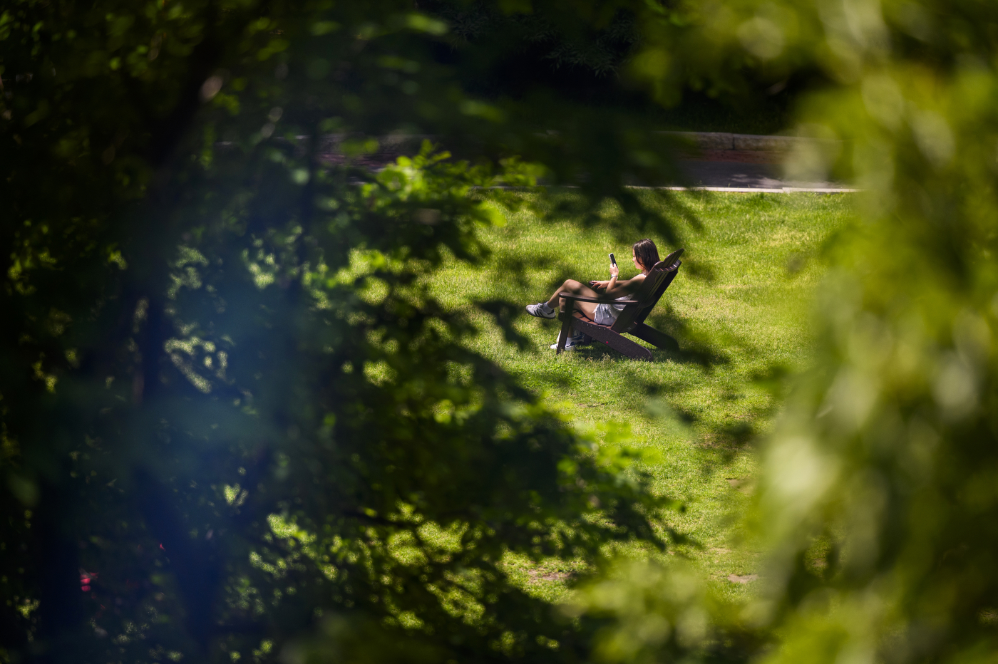 A person sits on a lawn chair outside on a sunny day.