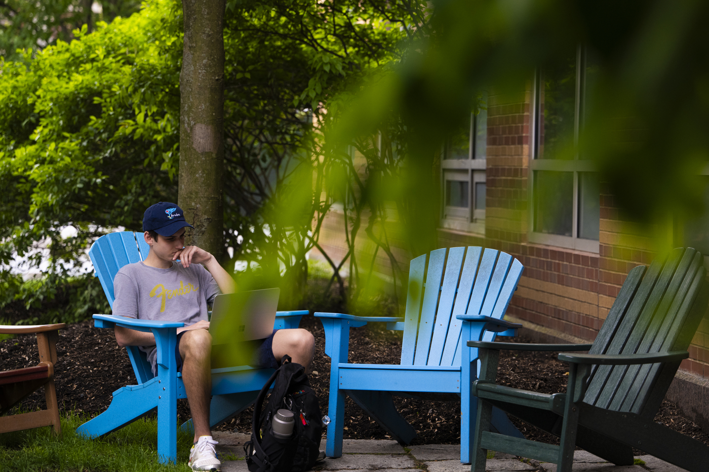 A person outside studying in a blue lawn chair.