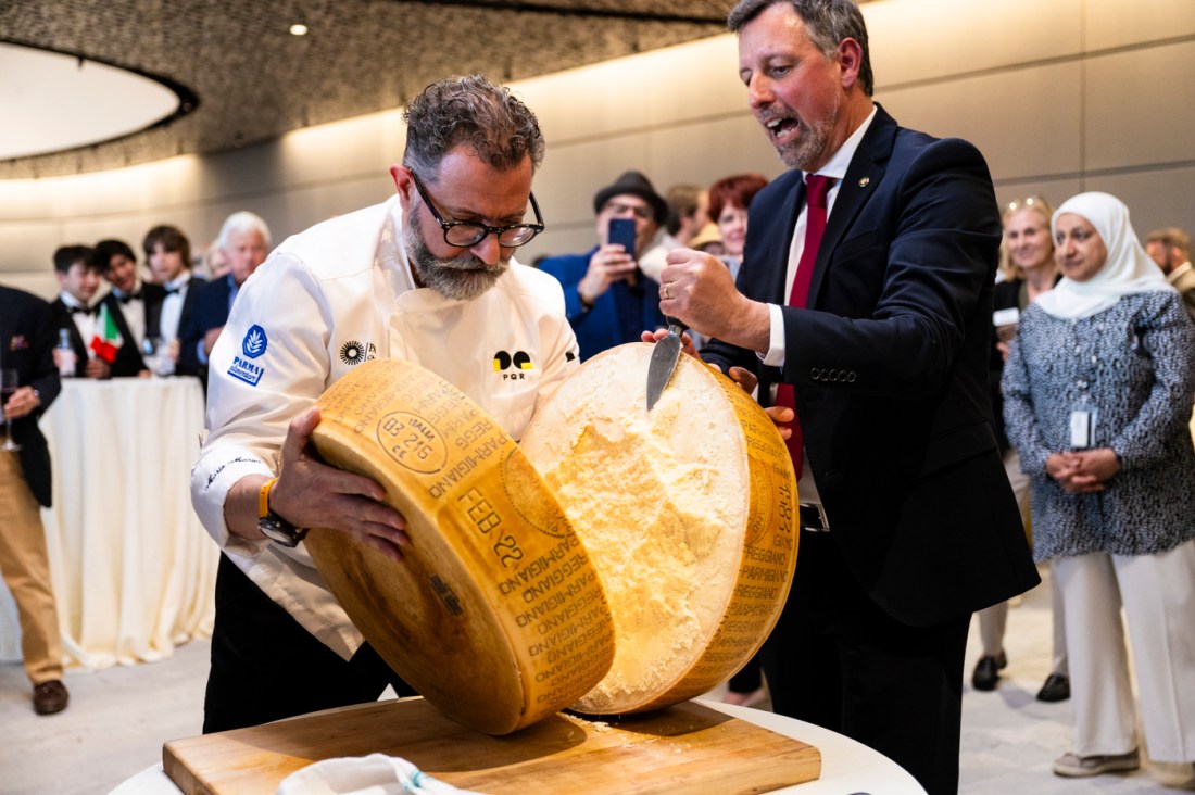 Mari Marini cutting a giant wheel of parmesan.