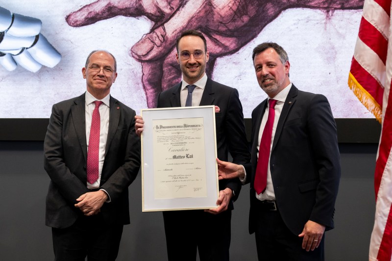 Matteo Lai holding a framed award standing next to two other people.