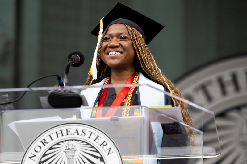 Rebecca Bamidele smiling at the podium in Commencement regalia