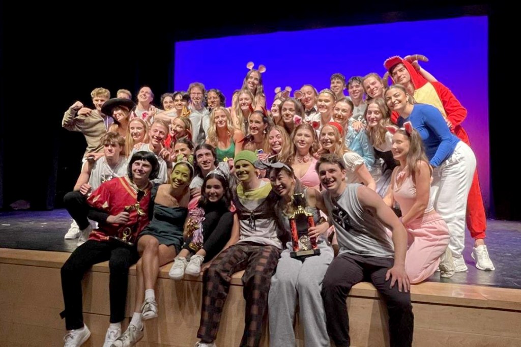 A group of Greek life members posing on a stage.