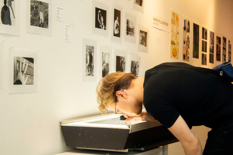 A student looking through a magnifying glass at a display of objects. 