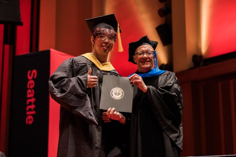 Two people take a picture at Seattle's Commencement ceremony.