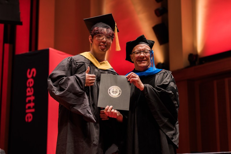 Two people take a picture at Seattle's Commencement ceremony. 