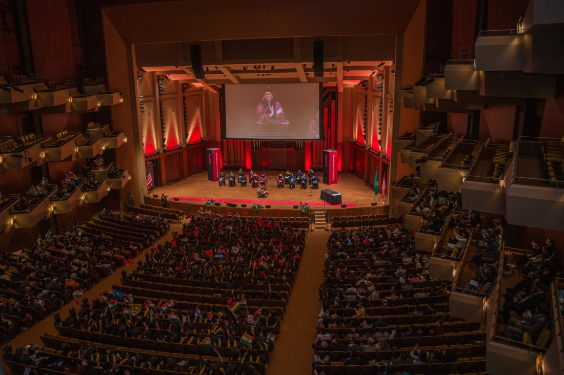 A person wearing regalia speaks at a podium at Seattle's Commencement ceremony. 