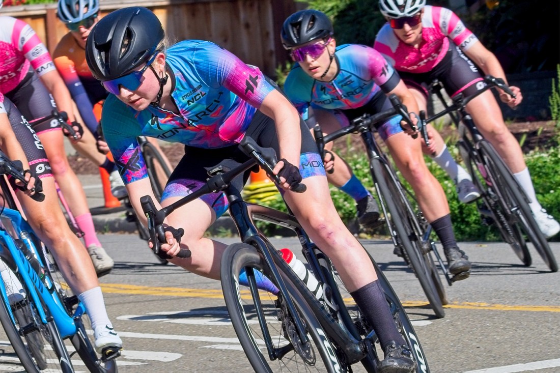 Helena Gilbert-Snyder cycling on the road with a group of other riders.