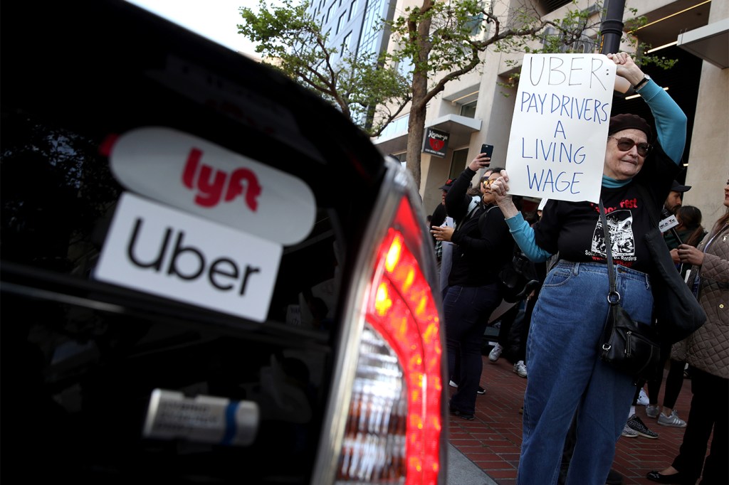 Protestors outside of a car with Lyft and Uber stickers on it.