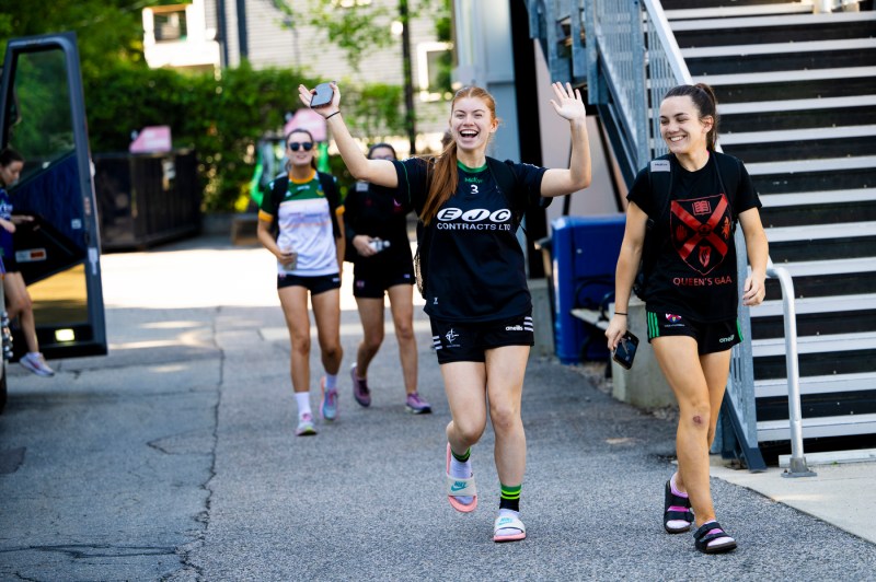 Queen's University Belfast women's Gaelic football team players smiling and waving.