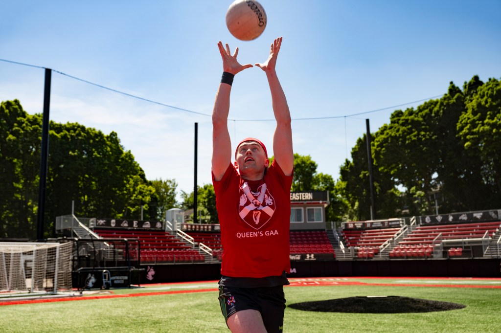 A person wearing a red shirt throws a white ball in the air.