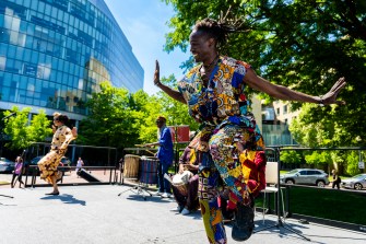 Members of a drum and dance group perform on a stage outside.