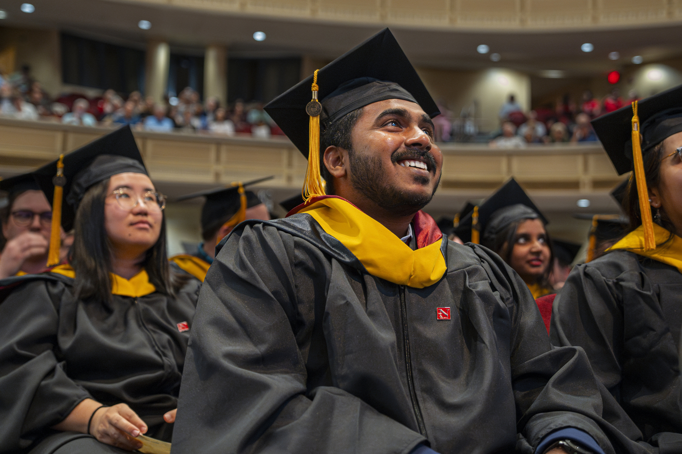 Graduates smiling and looking up on stage.