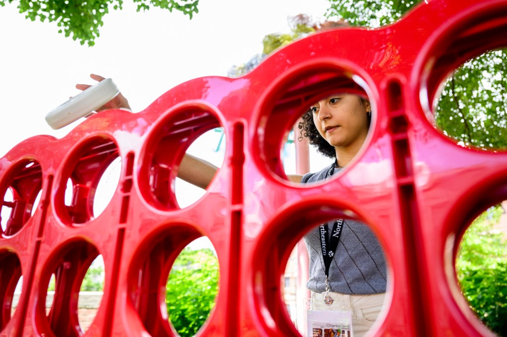 A person drops a giant Connect 4 piece into one of the slots on the red-colored game board.