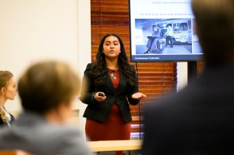 A student presents their project in front of a screen.