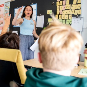 A teacher in a classroom calling on one of the students.