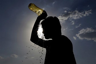 Silhouette of a boy dumping water on his head on a hot summer day.