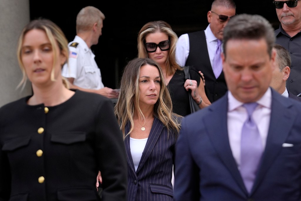 Karen Read walks out of a courthouse, followed by lawyers and working professionals.