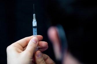 A person holding a COVID vaccine needle.