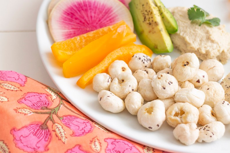 Colorful foods lie on a white plate, with AshaPops popped lily seeds on display. 