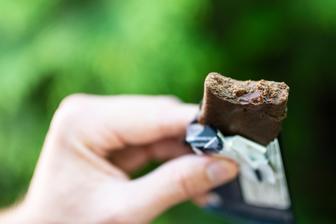 A hand holds a half-eaten seaweed protein bar from Phytabar.