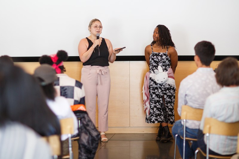 A person speaking into a microphone at the Summer Youth Employment Program ceremony.