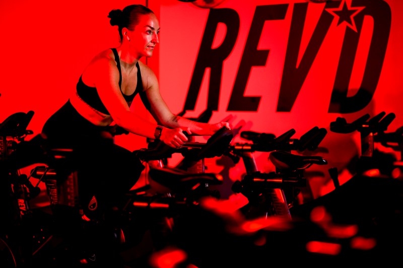 Meaghan St Marc poses for photos while sitting on cycling gym equipment.