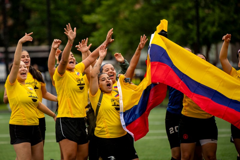 People in yellow jerseys holding a yellow blue and red striped flag cheering on Carter Field.