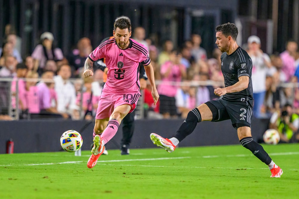 Soccer player Lionel Messi plays against Nashville SC defender Daniel Lovitz on a field during a professional game.